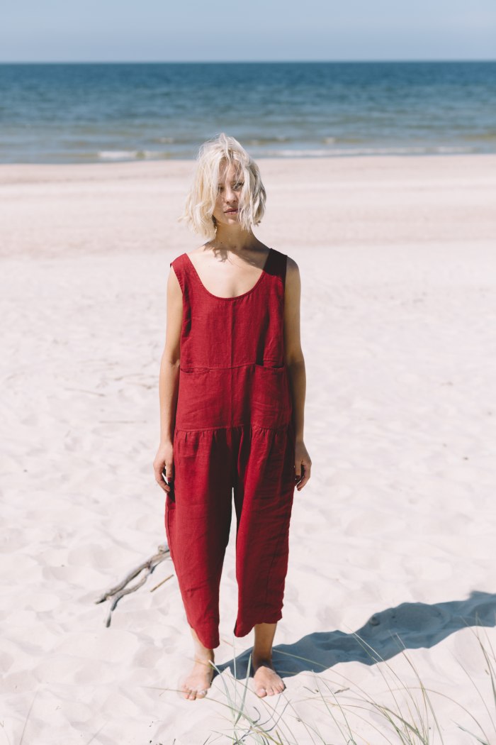 Blond girl wearing red linen jumpsuit at the beach