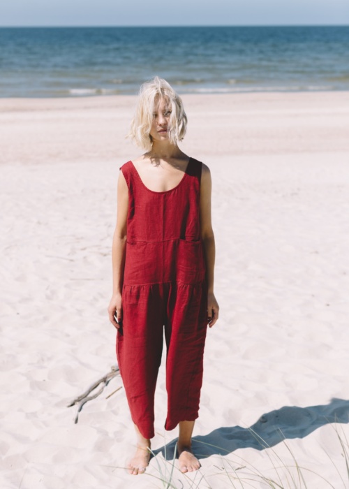 Blond girl wearing red linen jumpsuit at the beach