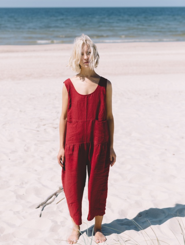 Blond girl wearing red linen jumpsuit at the beach