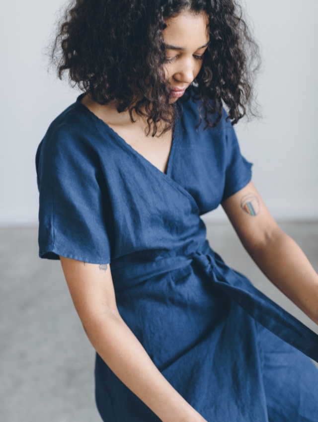 A woman on a chair in navy blue linen wrap dress