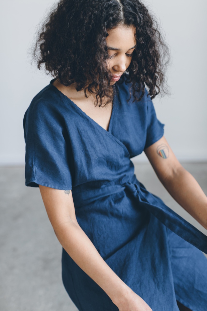 A woman on a chair in navy blue linen wrap dress