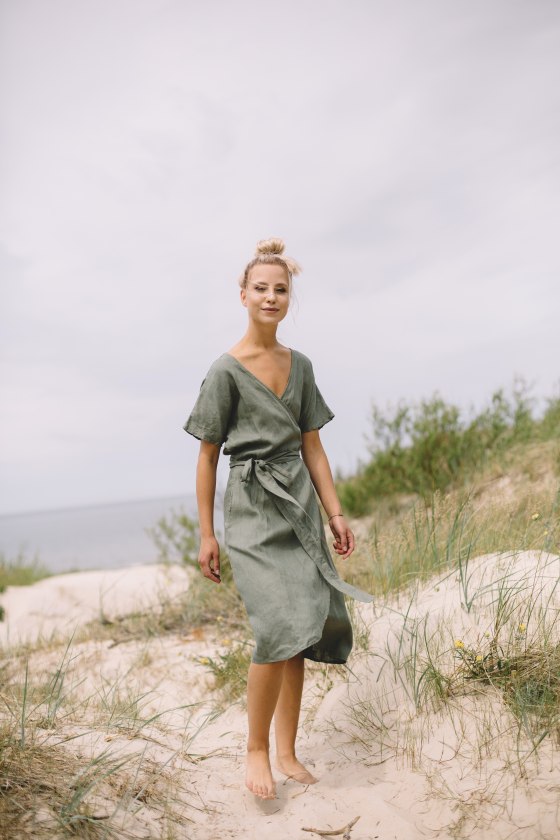 A woman in a green linen wrap summer dress
