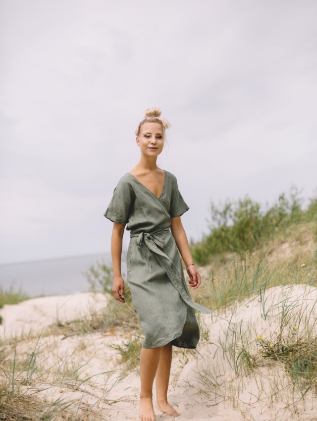 A woman in a green linen wrap summer dress