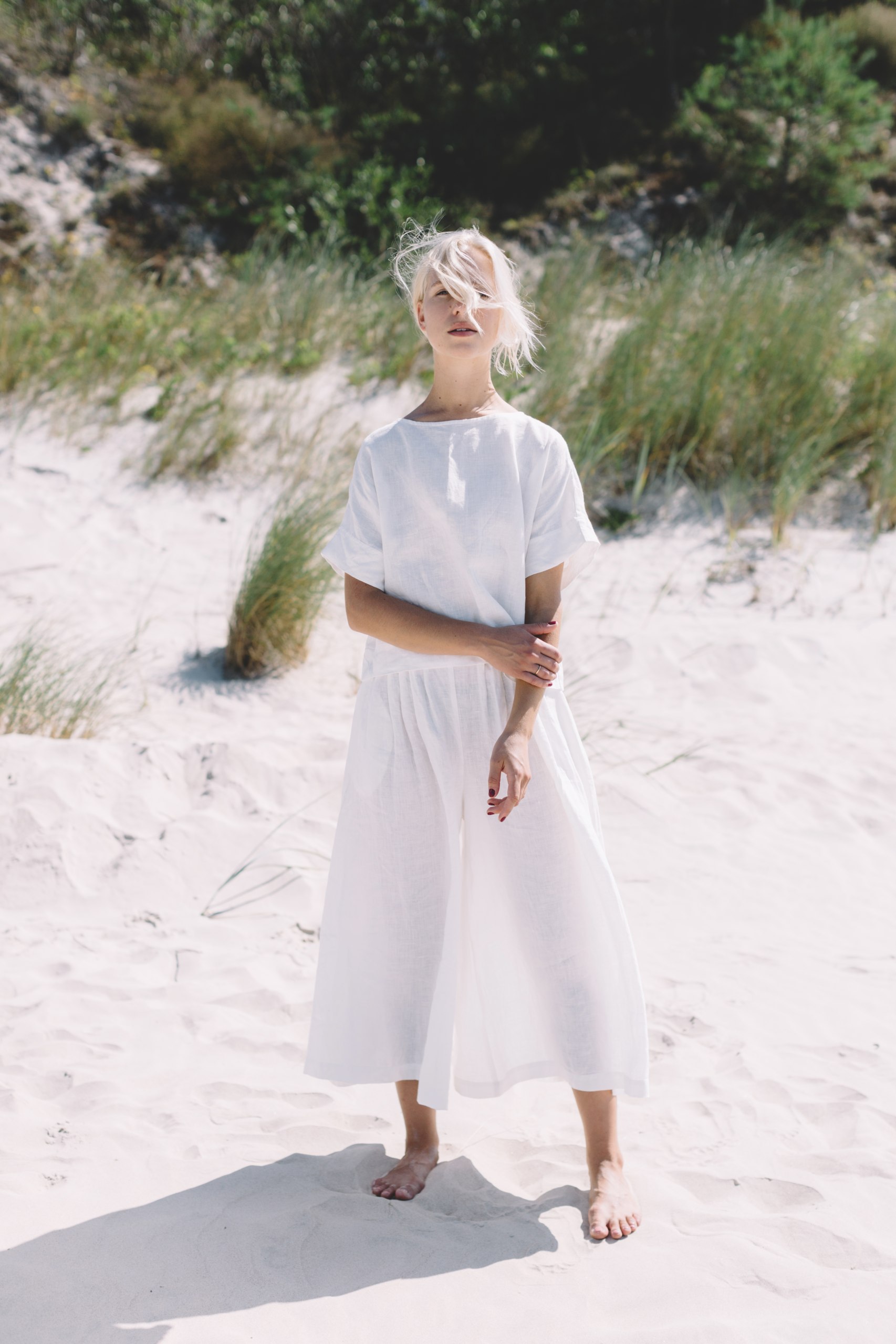 A woman in white straight cut linen top and matching trousers