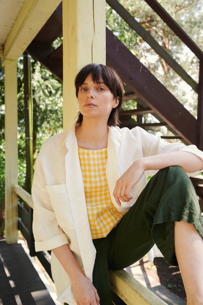 A woman sitting in linen oversized button down shirt in white