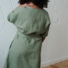 Back of model in a green oversized linen dress with a belt