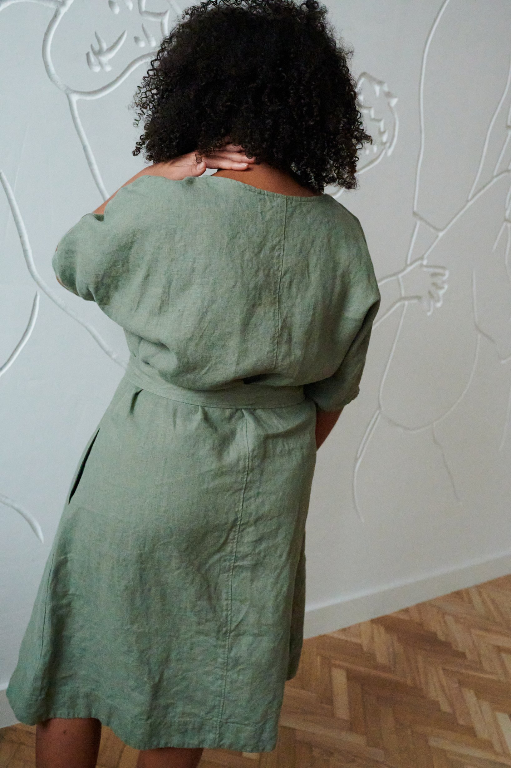 Back of model in a green oversized linen dress with a belt