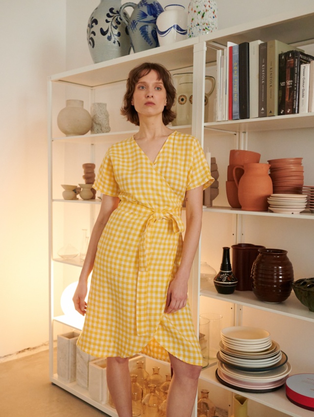 a woman wearing a yellow gingham wrap dress