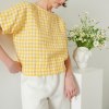 A woman wearing straight but oversized yellow gingham linen top