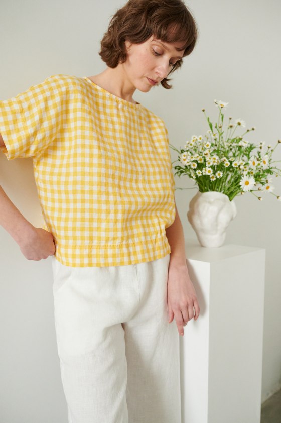 A woman wearing straight but oversized yellow gingham linen top