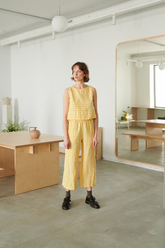 A model in yellow gingham high waist linen trousers and a matching top
