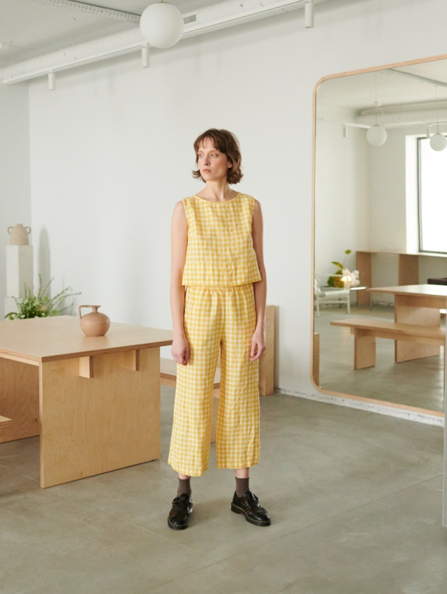 A model in yellow gingham high waist linen trousers and a matching top