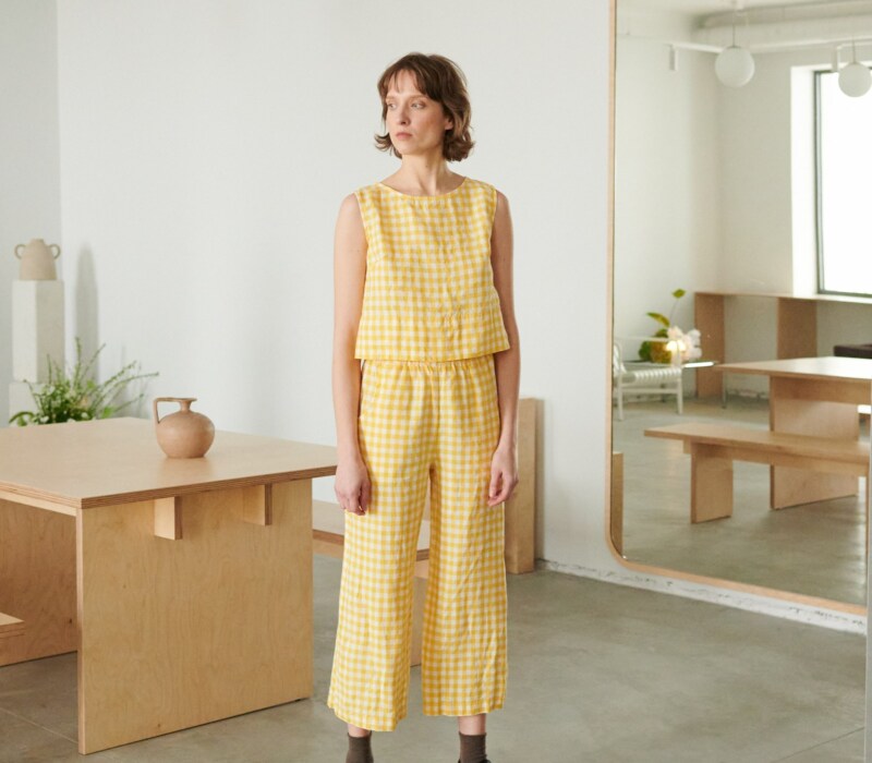 A model in yellow gingham high waist linen trousers and a matching top
