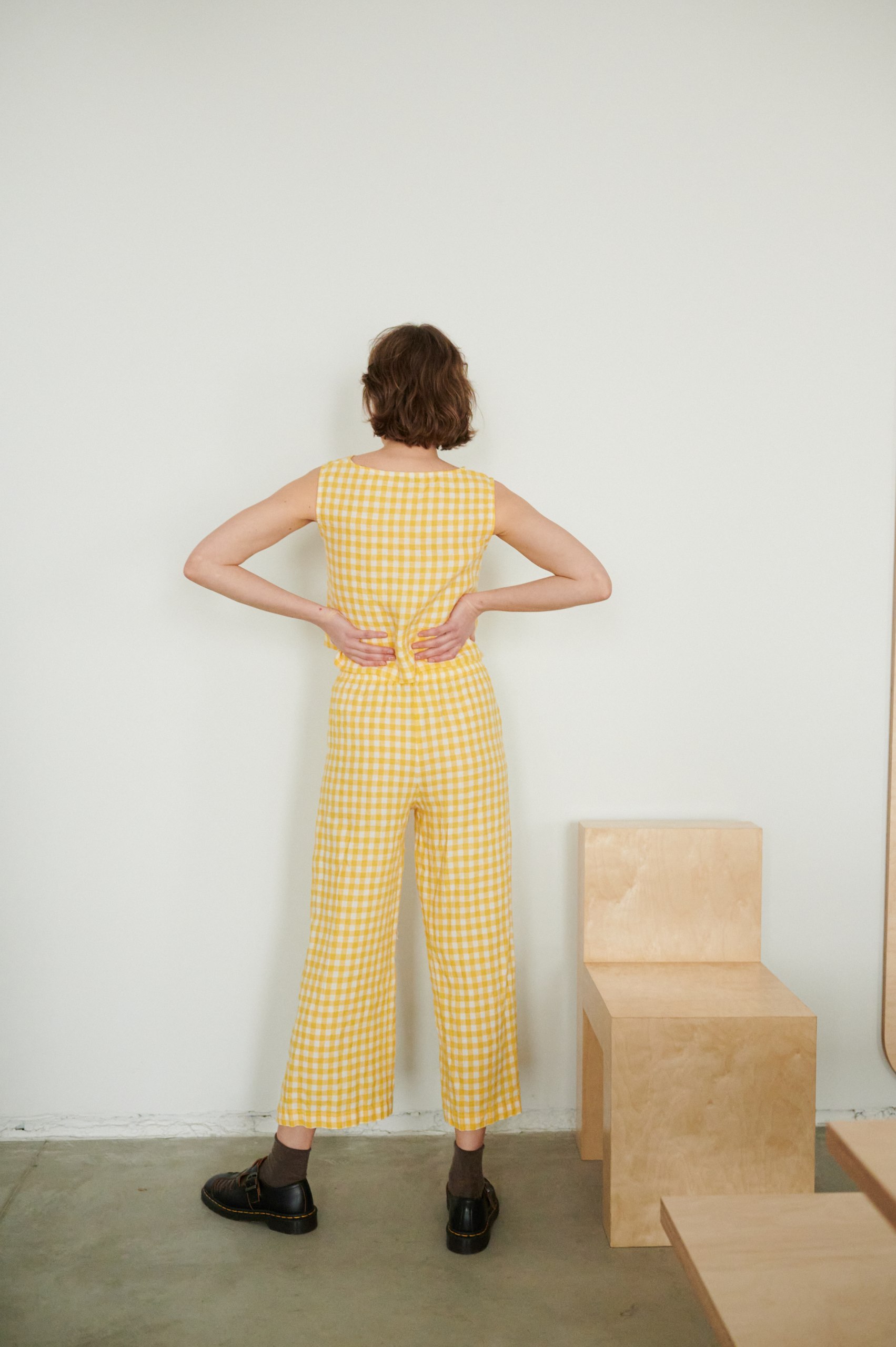 A woman wearing wide leg linen yellow gingham trousers and a matching top