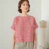 A woman in red gingham boxy linen top