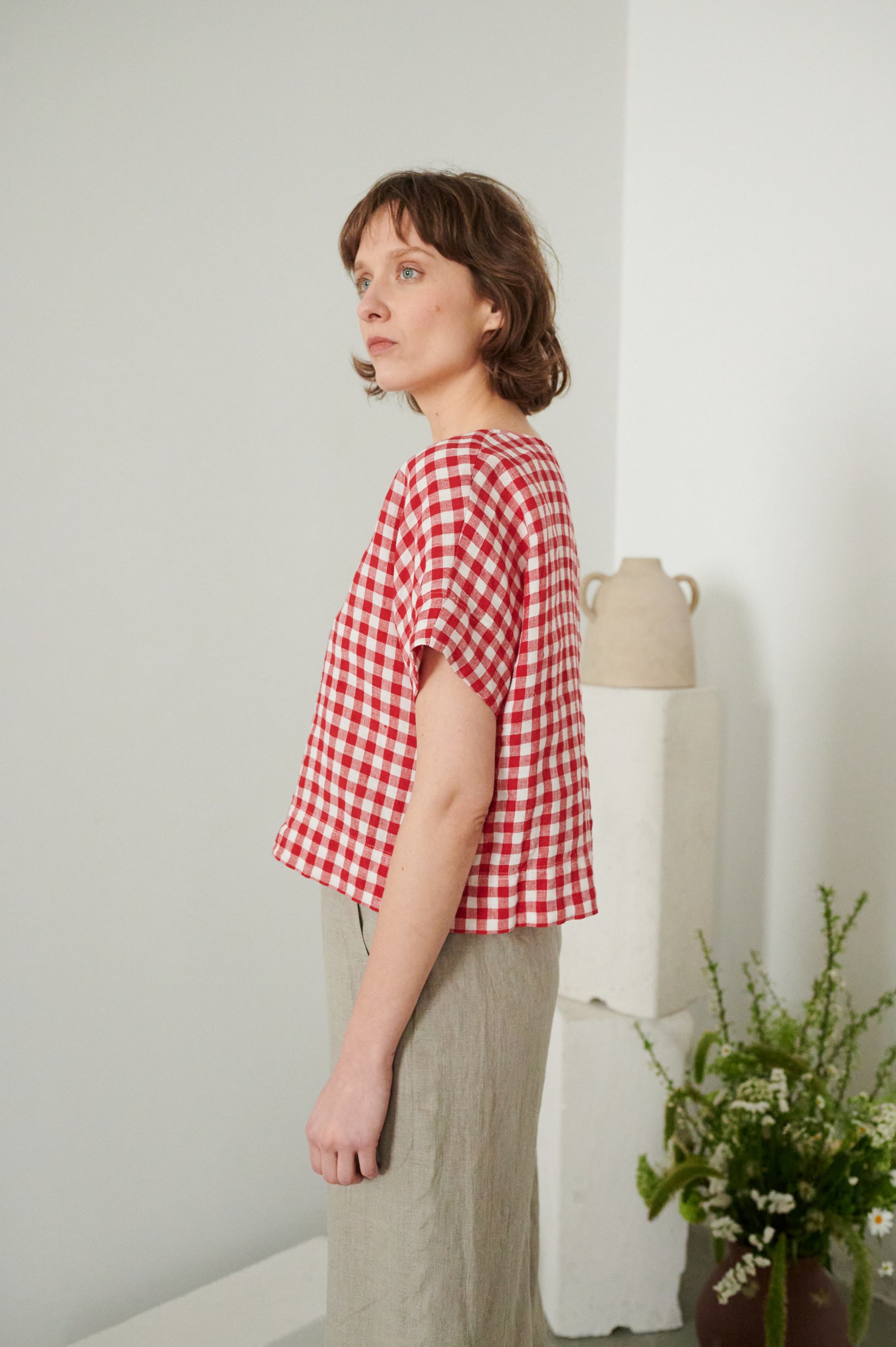 Linenfox model wearing a short sleeve boxy linen top in red gingham