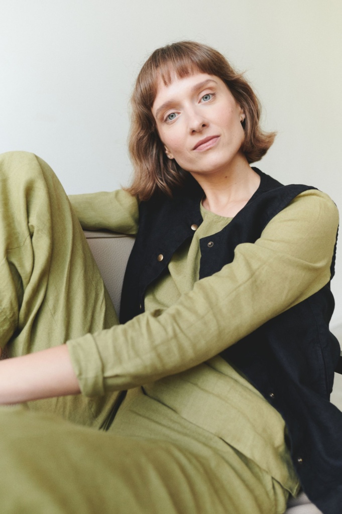 Model in an olive green linen top and trousers outfit paired with a black linen vest
