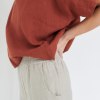 A woman in boxy oversized linen top in terracotta brown