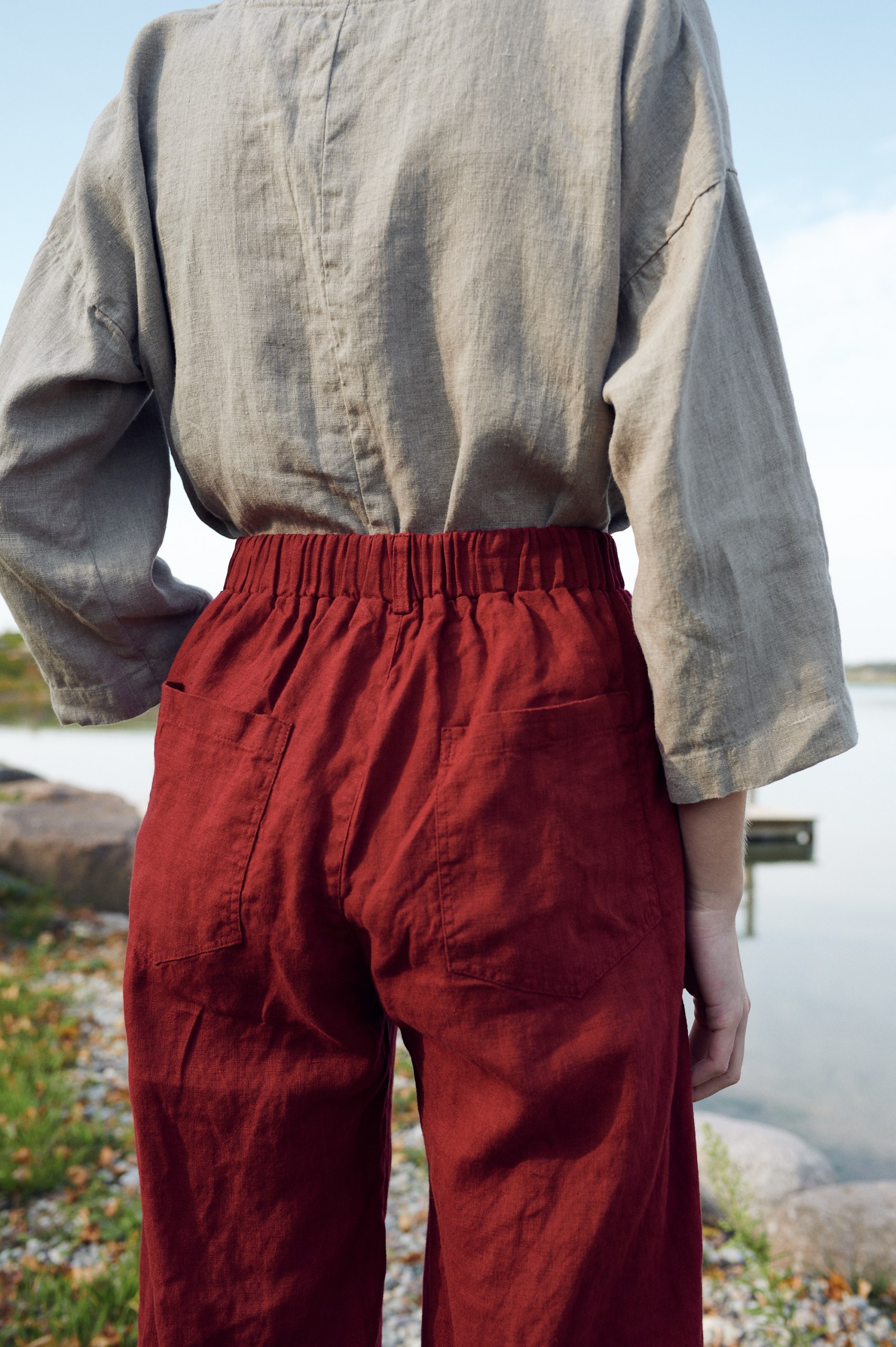 The elasticated back of dark red linen barrel trousers