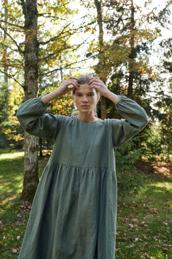 A woman in pine green long sleeve linen dress