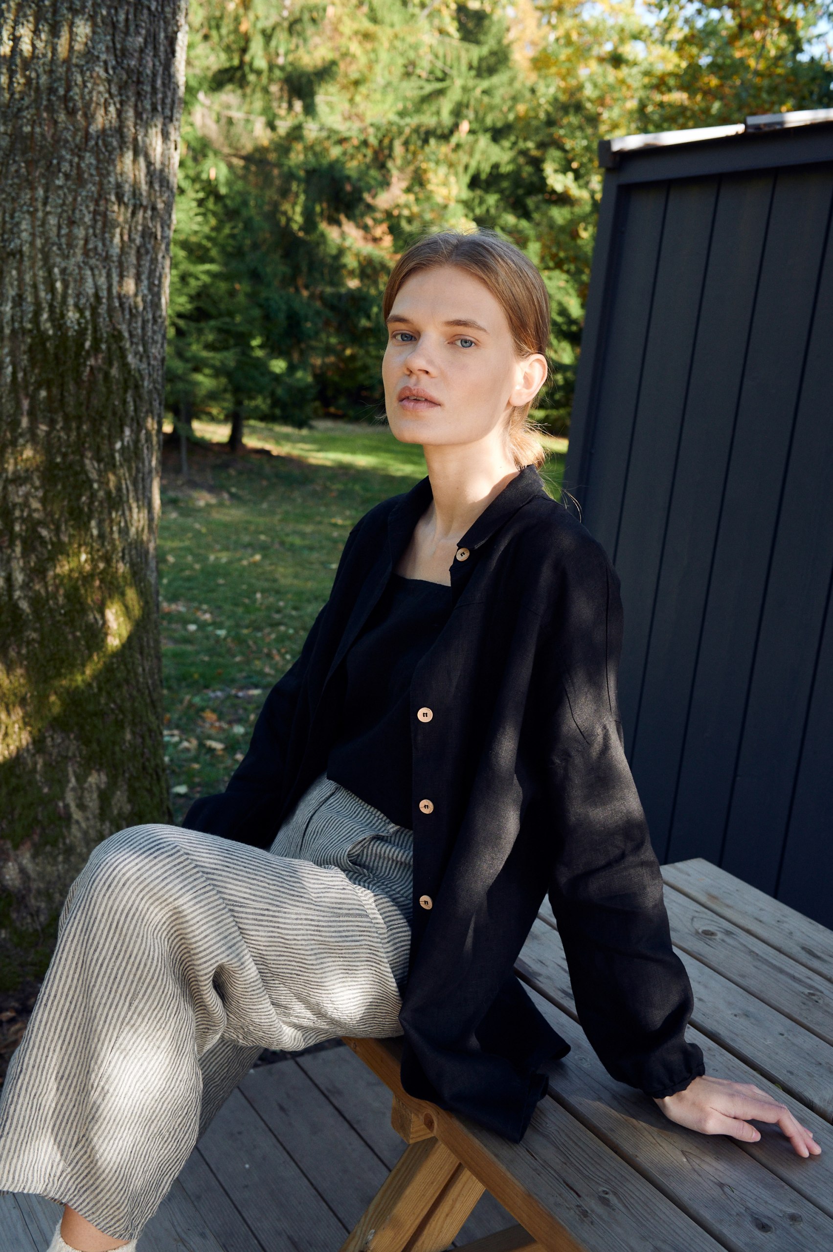 A woman sitting in grey stripe linen trousers