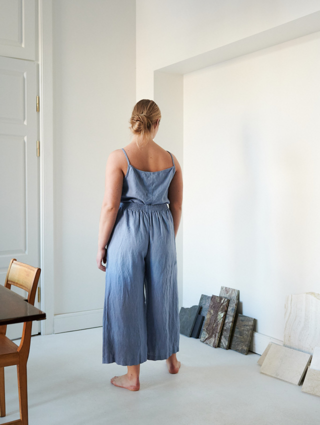 The back of a model wearing wide leg blue linen trousers