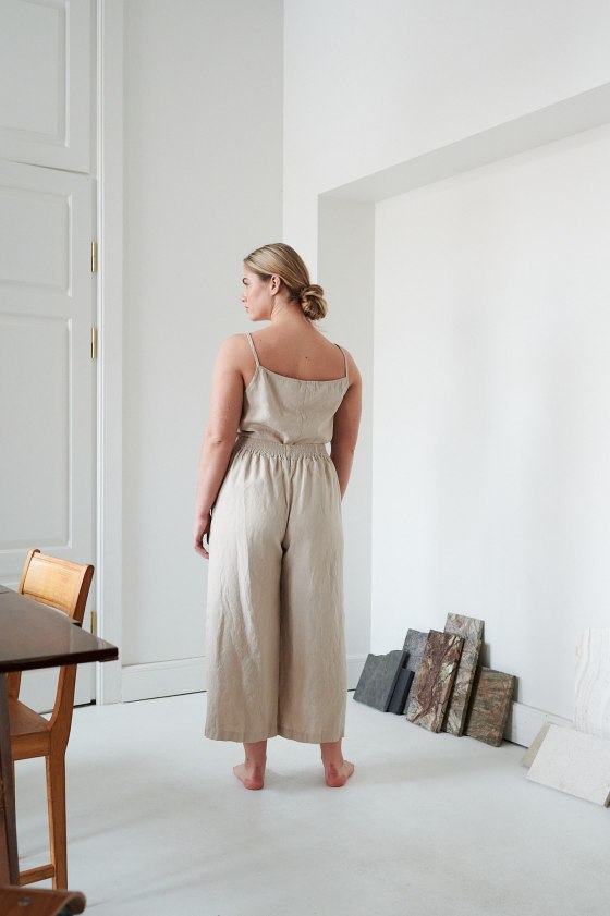 The back of the model wearing relaxed beige linen pants