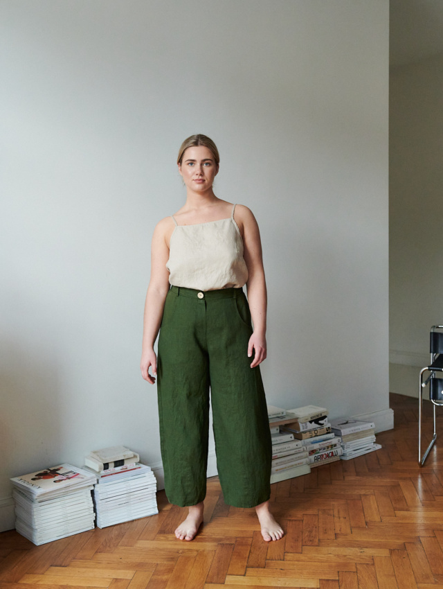 A woman in barrel leg heavy linen trousers in green