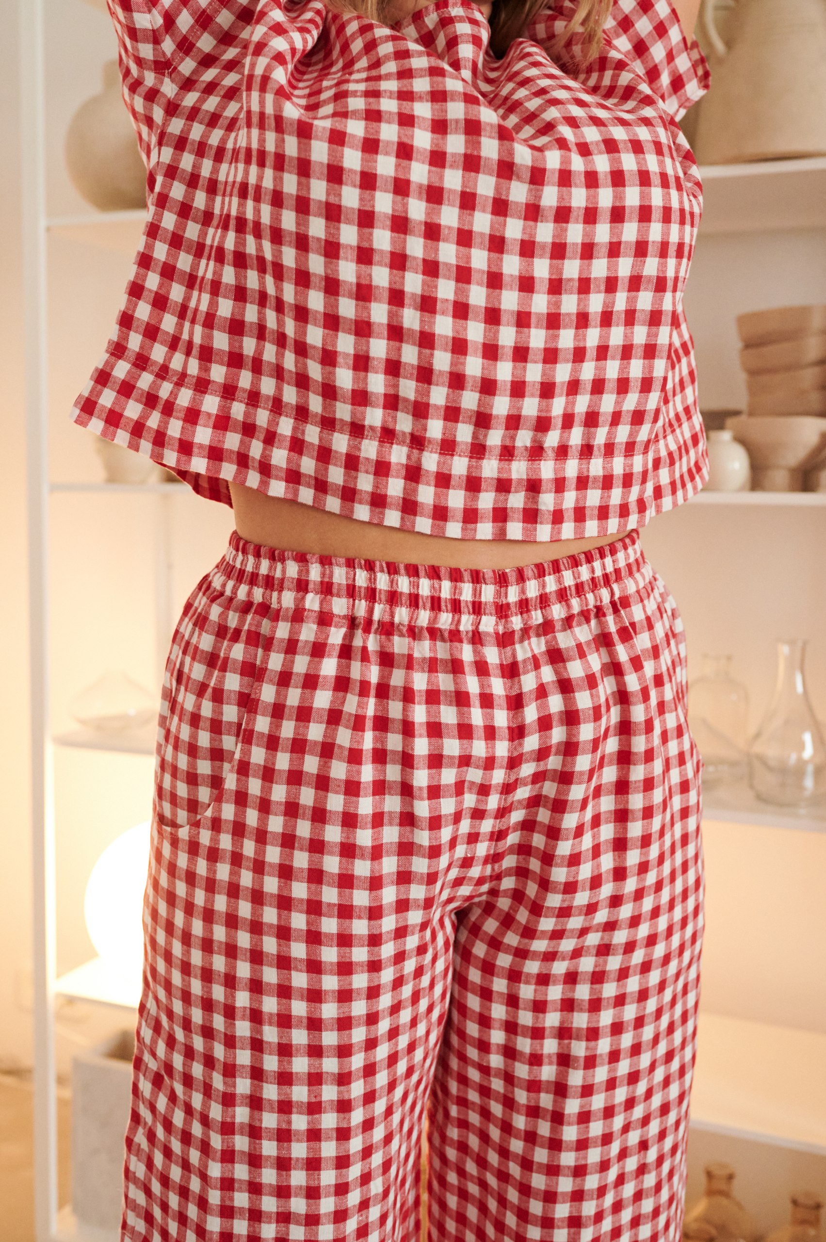 The elasticated waistband of summer linen trousers in red gingham