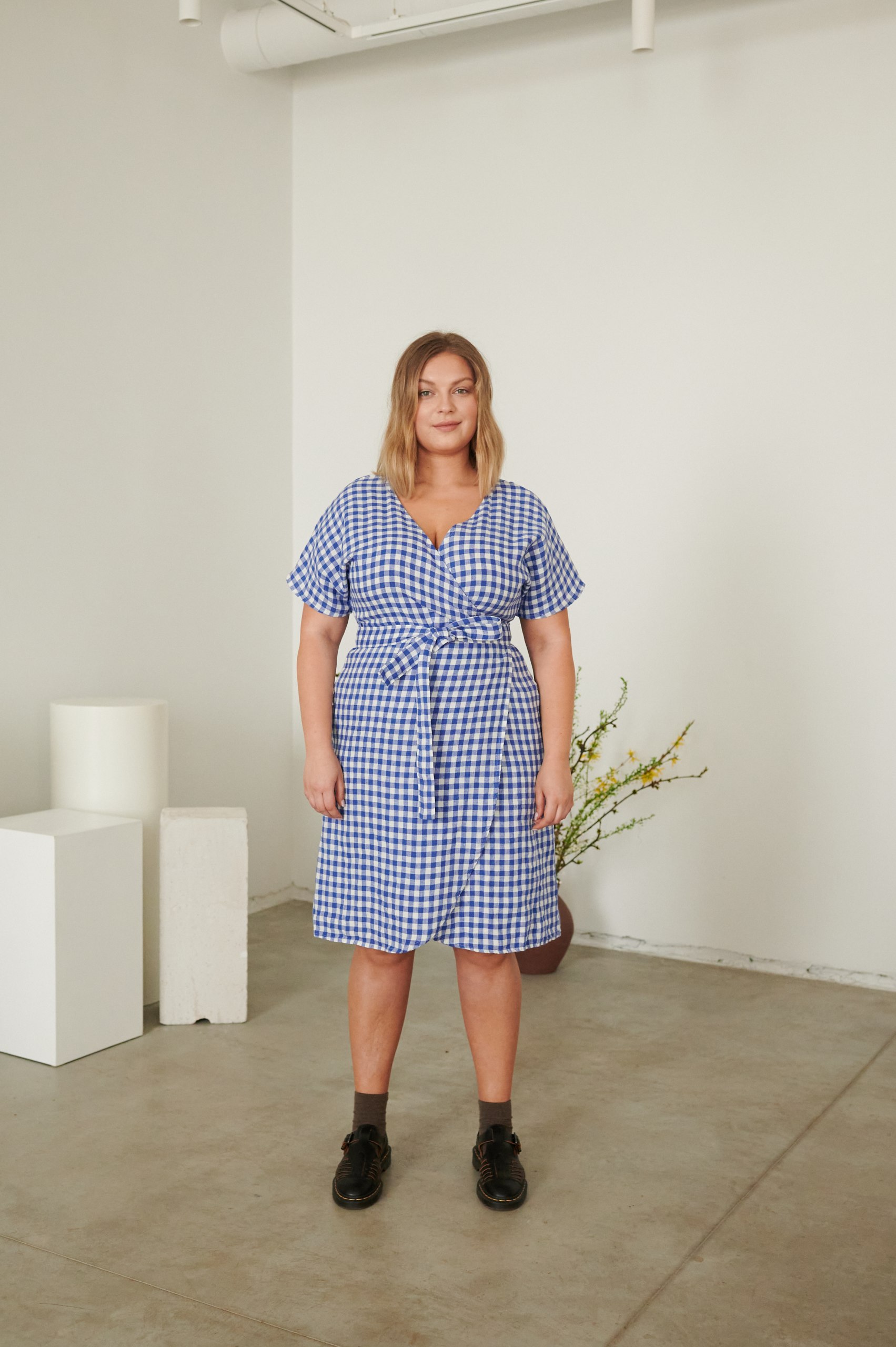 a woman in blue gingham wrap dress
