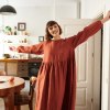 A woman in terracotta oversized smock linen dress