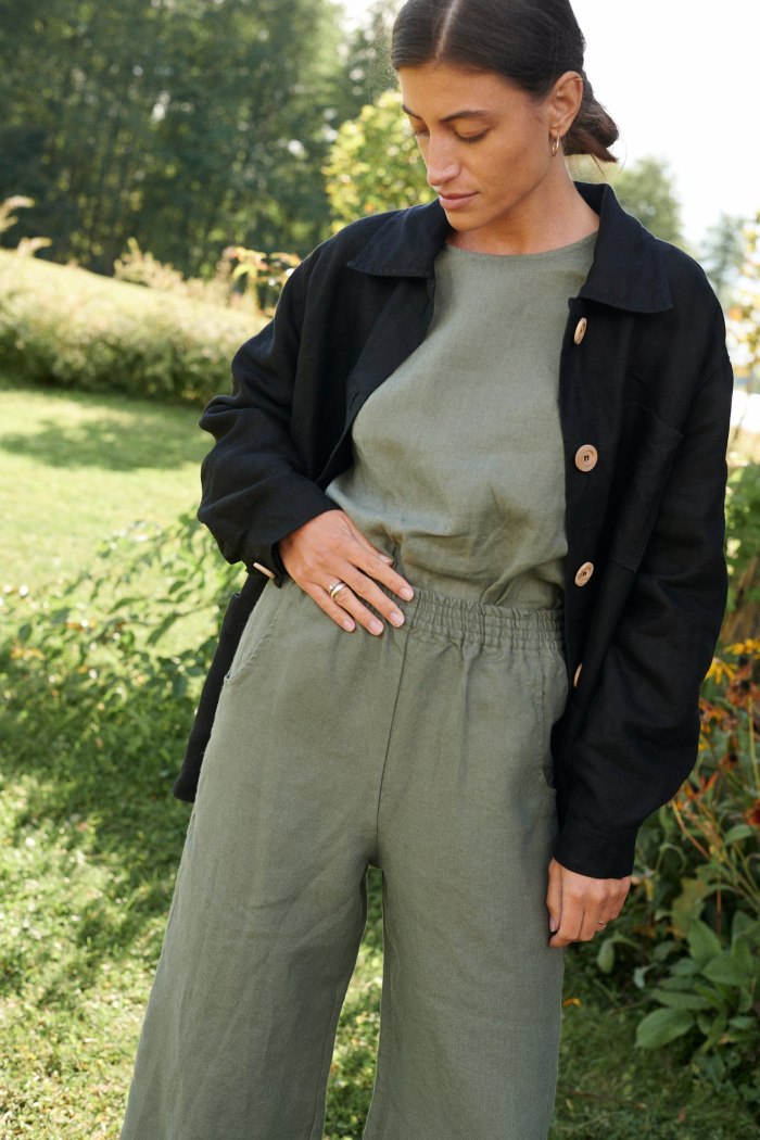 The elasticated waistband of wide leg linen trousers in pine green
