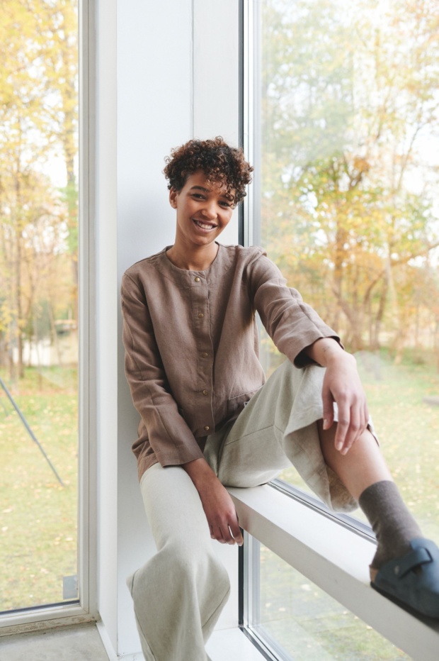 Girl sitting on windowsill dressed up with linen clothes