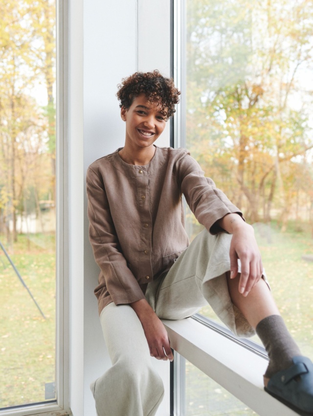 Girl sitting on windowsill dressed up with linen clothes