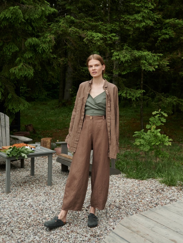 A woman standing in brown wide leg heavy linen pants