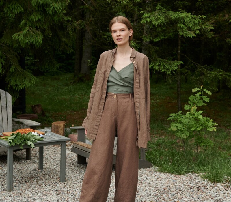 A woman standing in brown wide leg heavy linen pants
