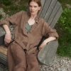 A woman sitting in brown heavy linen trousers and brown shirt