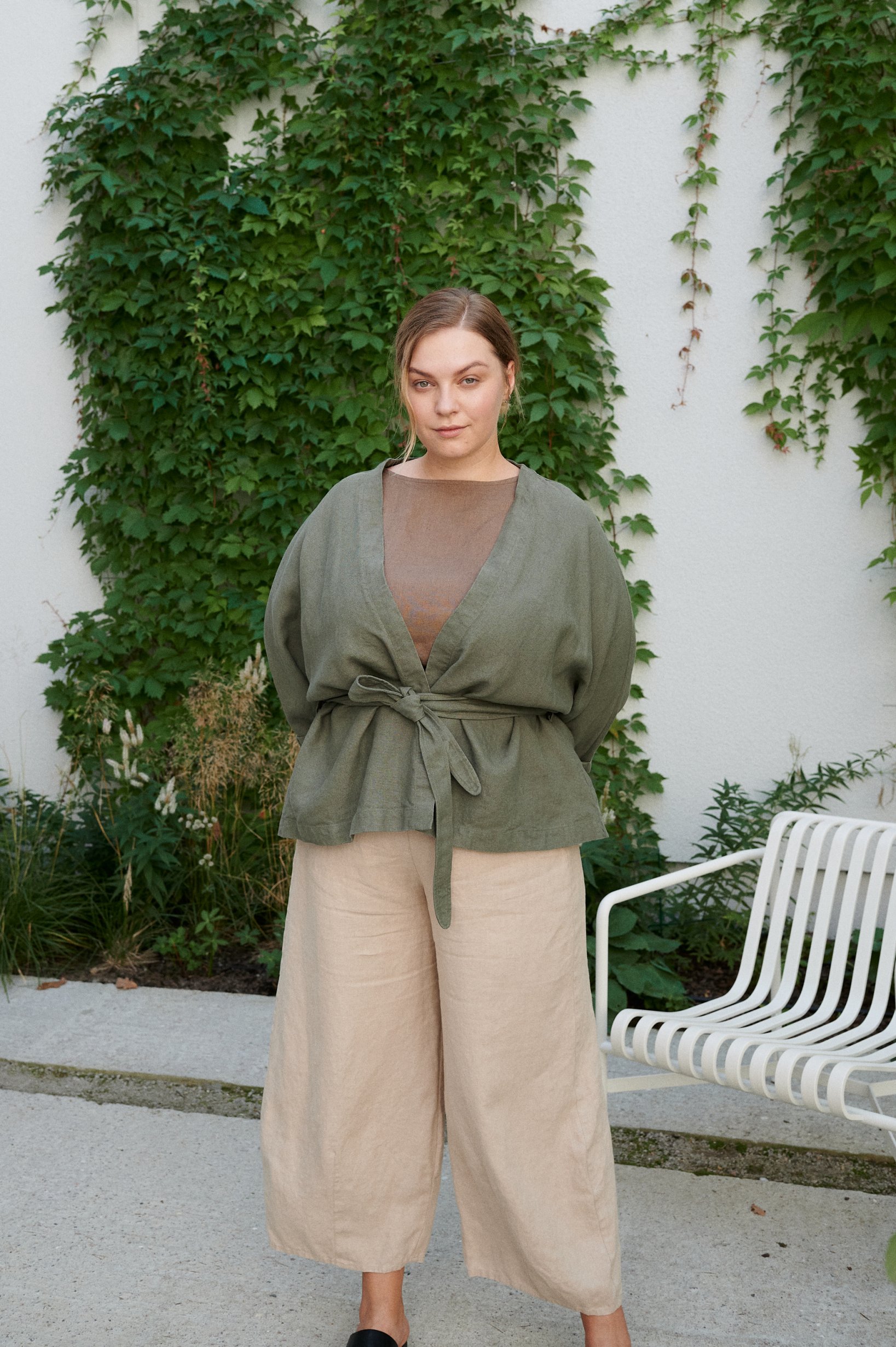 Woman in a heavy linen relaxed fit green jacket tied with a matching belt