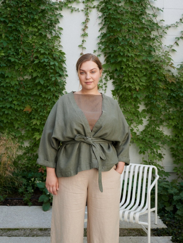 Woman wearing a pine green heavy-weight linen jacket tied with s belt