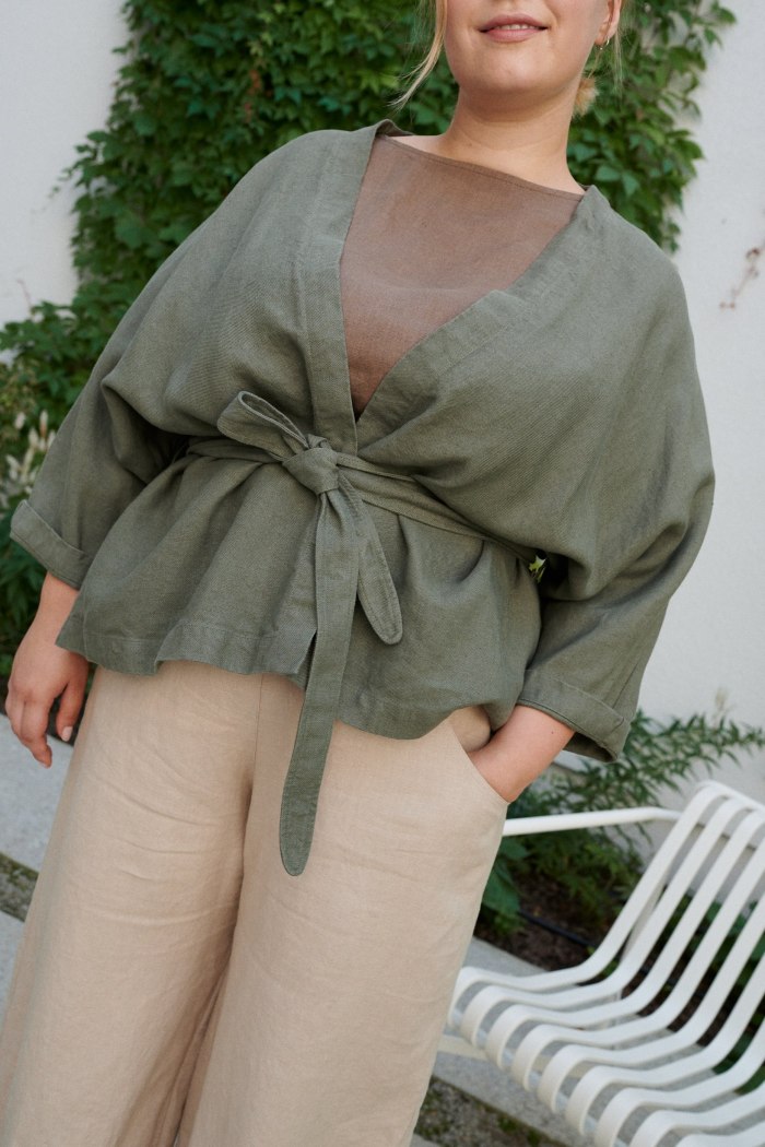 Details of a green kimono style linen jacket with a high-low hem