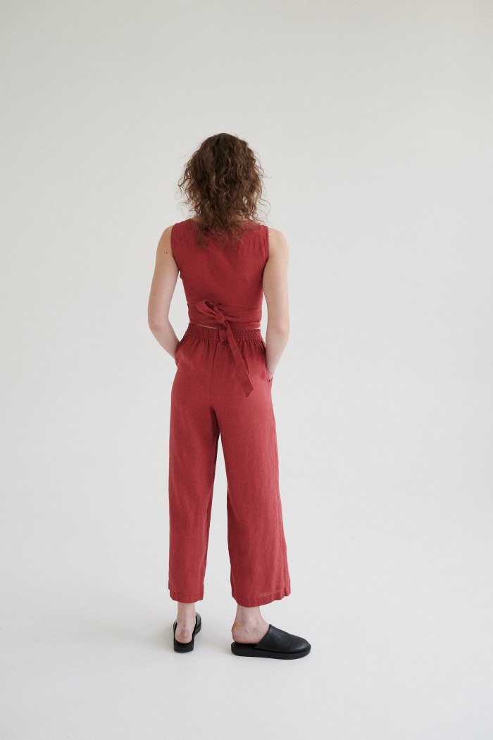 Back of a woman in wide-leg linen trousers and a matching sleeveless wrap linen top