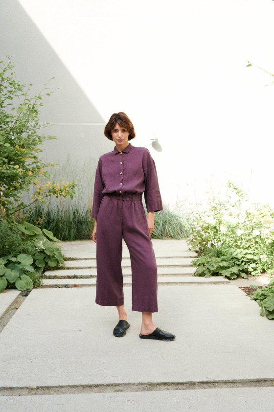 A woman in a button-down linen jumpsuit with a dress shirt collar and an elasticated waistband
