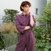 A model wearing a violet linen jumpsuit with an elasticated waist and wooden buttons