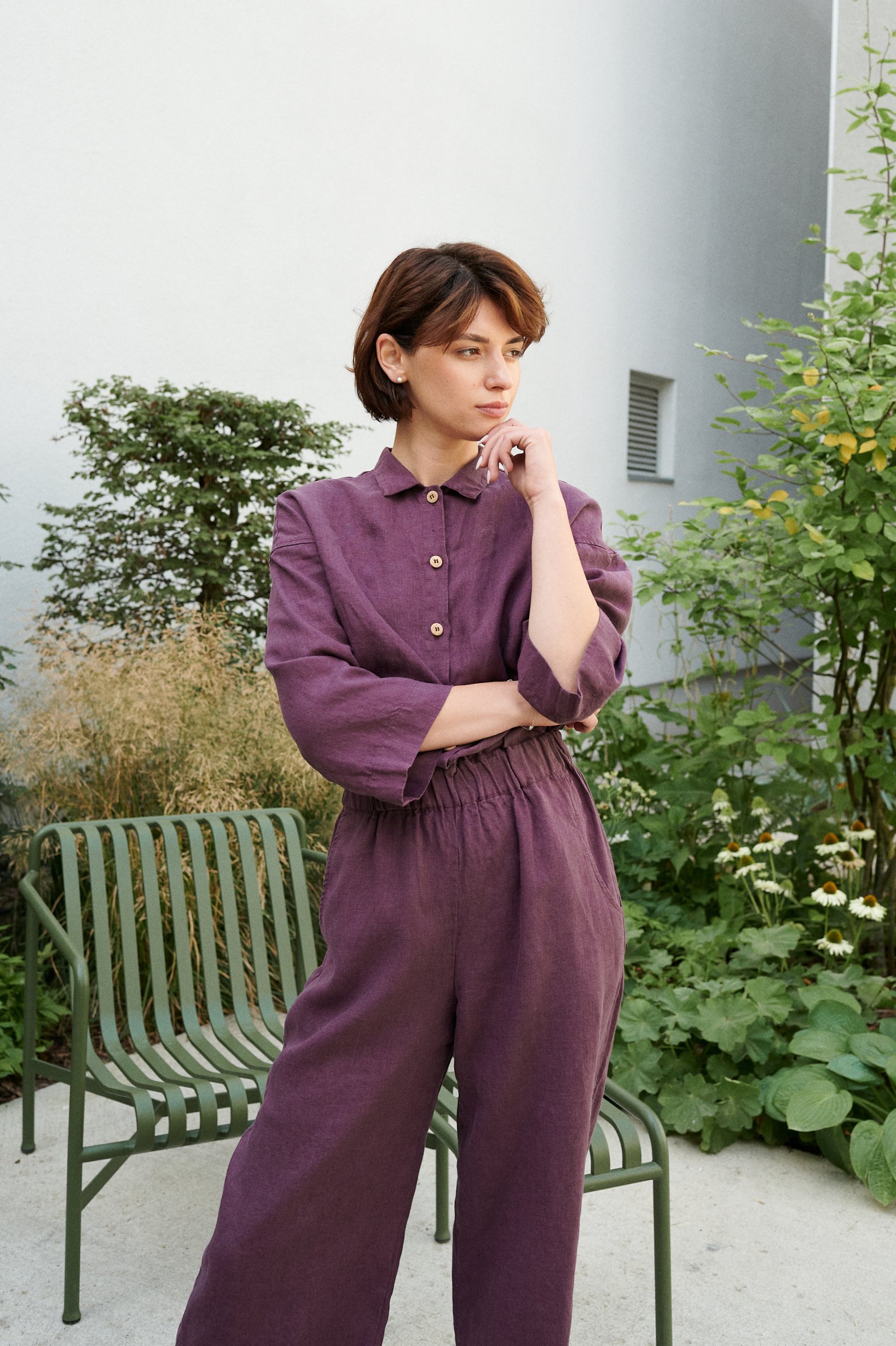 A model wearing a violet linen jumpsuit with an elasticated waist and wooden buttons