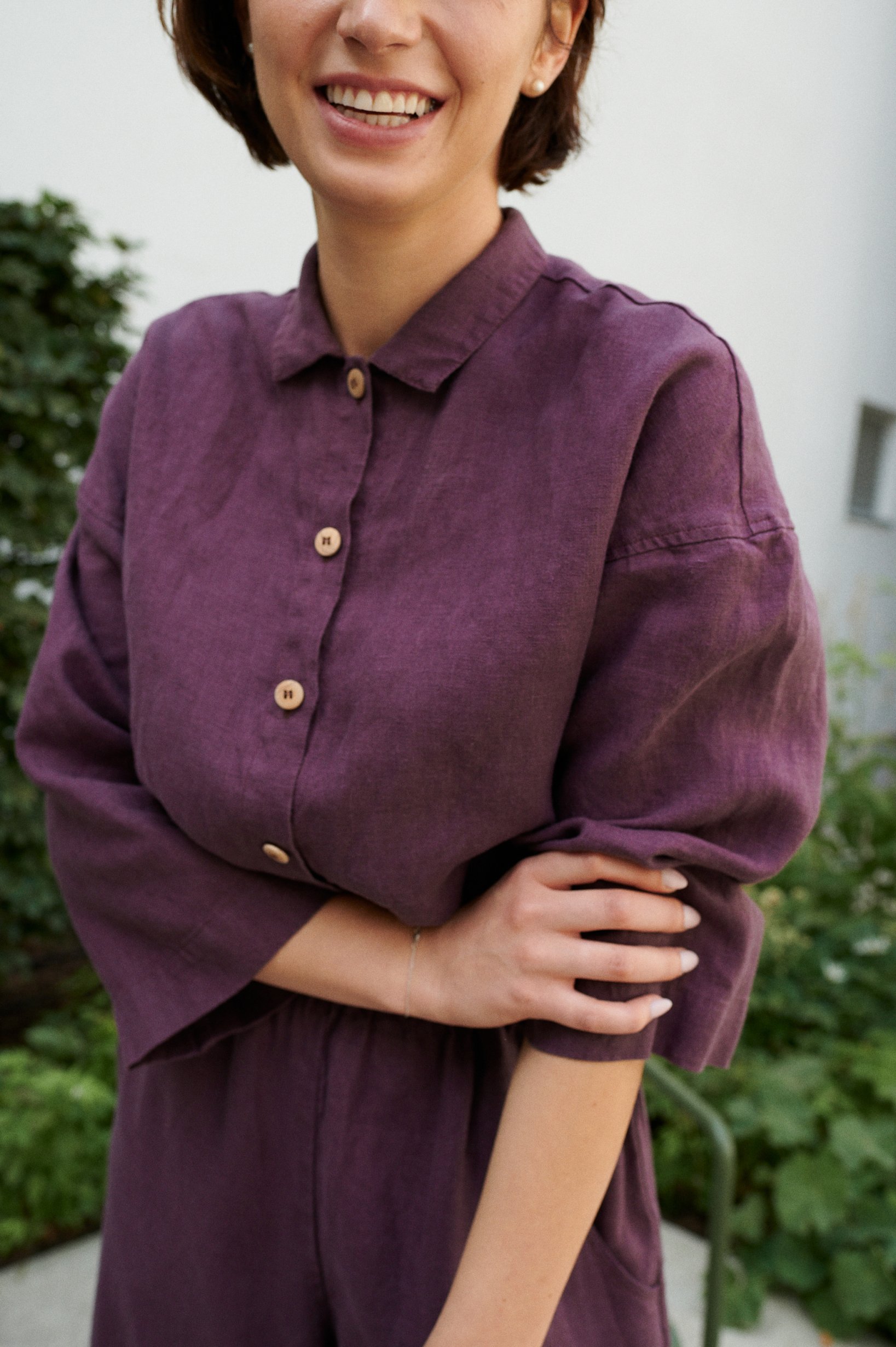 A button-down linen jumpsuit with a dress shirt collar and wooden buttons