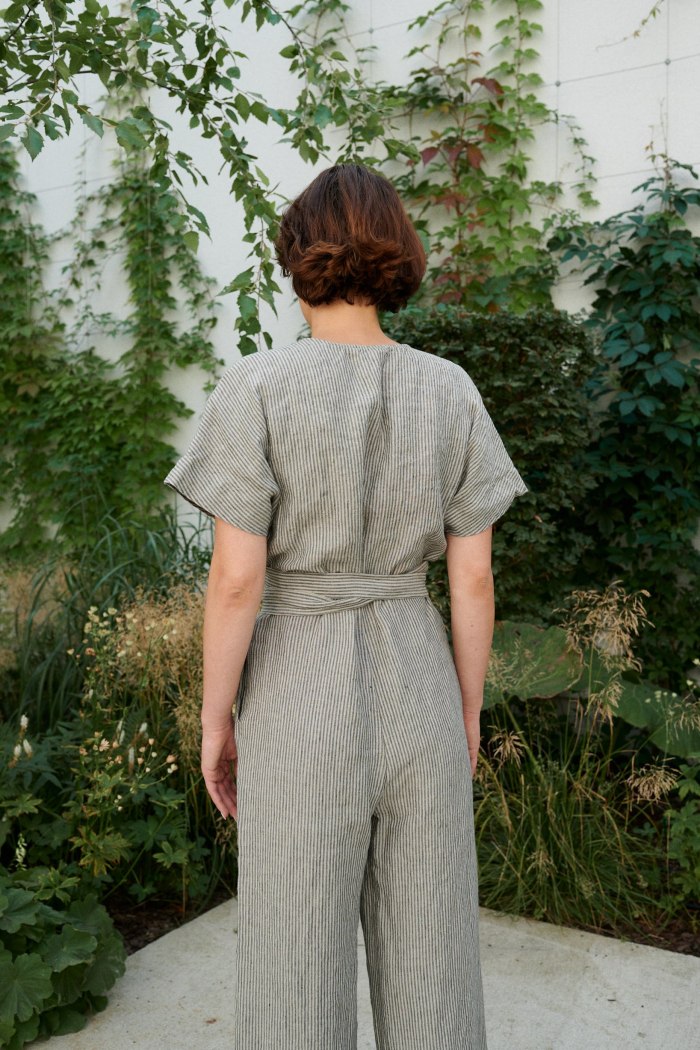 Back of a model in a relaxed fit linen jumpsuit with a belt