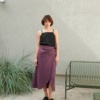 Woman wearing a violet mid-length linen wrap skirt and a black linen top