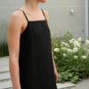 A black linen dress with thin spaghetti straps and a straight neckline