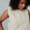 A model in a relaxed sleeveless linen top with a wide hem