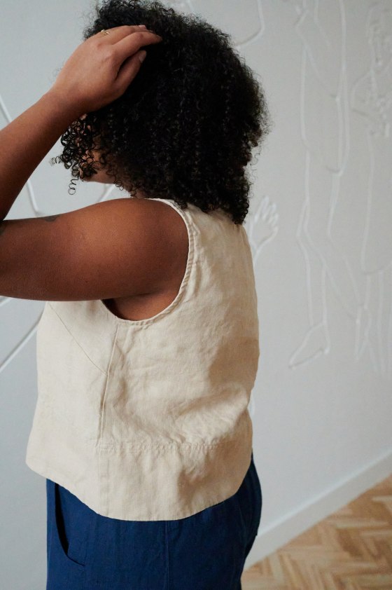 Side of a model in a beige sleeveless casual linen top